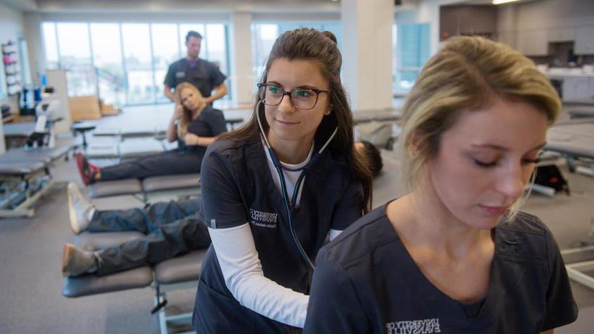 PA student in glasses using stethoscope